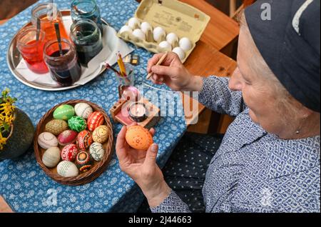 Dissen, Germany. 05th Apr, 2022. Babette Zenker, director of the Lower Sorbian Museum of Local History in Dissen, wears a Sorbian-Wendish working costume and decorates Easter eggs using the wax batik technique. (to dpa With quill and wax: Easter egg painting in Sorbian) Credit: Patrick Pleul/dpa/17�Թ����� Live News Stock Photo