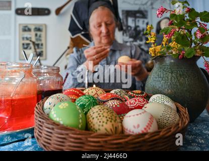 Dissen, Germany. 05th Apr, 2022. Babette Zenker, director of the Lower Sorbian Museum of Local History in Dissen, wears a Sorbian-Wendish working costume and decorates Easter eggs using the wax batik technique. (to dpa With quill and wax: Easter egg painting in Sorbian) Credit: Patrick Pleul/dpa/17�Թ����� Live News Stock Photo