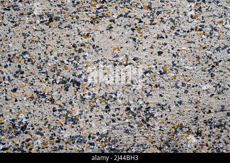 Closeup of cream, brown and black granite speckles on old wall in Indonesia Stock Photo