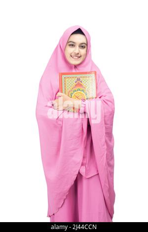 Asian Muslim woman in a veil standing and holding the Quran isolated over white background Stock Photo