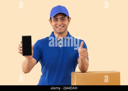 Portrait of a courier delivery boy showing Smartphone and gesturing with thumb Stock Photo