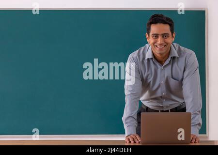 Portrait of a smiling school teacher looking at camera during online class Stock Photo
