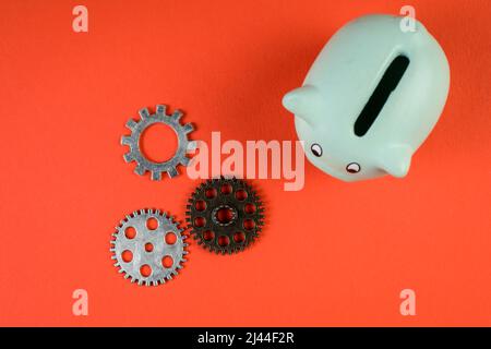 Gears and piggy bank on a red background. Money saving concept. Stock Photo