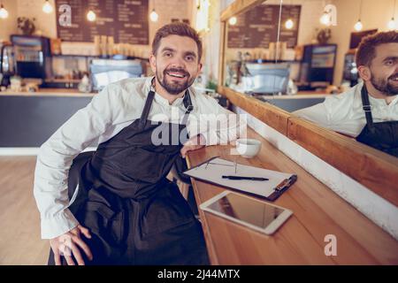 Cheerful bearded man working in coffee shop Stock Photo