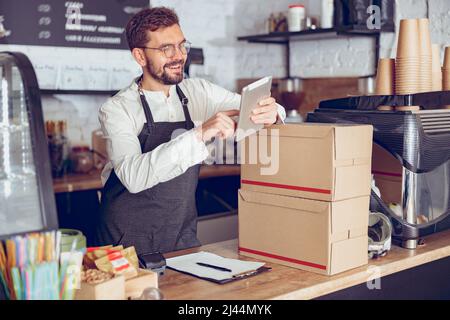 Cheerful male barista using tablet computer in cafe Stock Photo