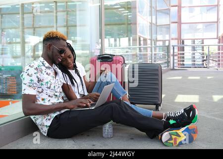 Young african couple checking their travel information on a laptop. Stock Photo