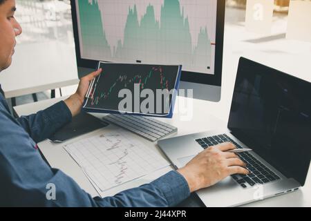 Close up of hand investors are pointing to laptop computer that have investment information stock markets and partners taking notes and analyzing perf Stock Photo
