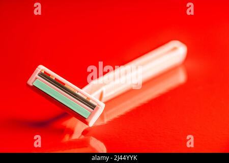 Pink women's razor on a red background. Stock Photo