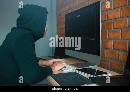 Hacker in the hood working with computer with hacking breaking into data servers. Stock Photo