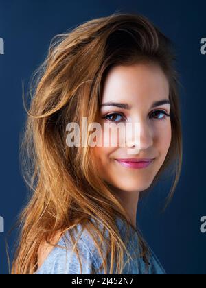 Shes got an easygoing spirit. Studio portrait of a cute teenage girl smiling and posing against a dark background. Stock Photo