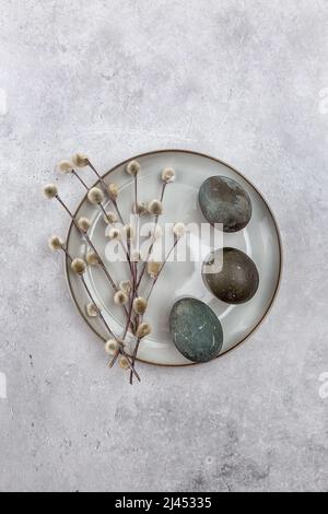 Easter picture with painted eggs on a plate. Willow branch. The minimal concept of Easter. An Easter card with a place for the text. Stock Photo