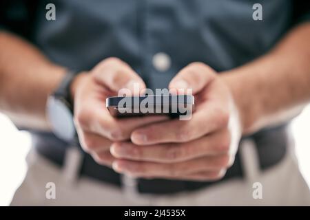 Putting the pieces together. Shot of an unrecognizable businessman using a smartphone in a modern office. Stock Photo