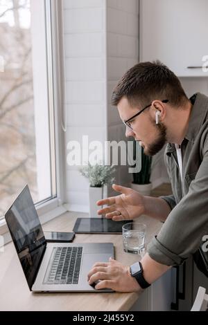 Serious young businessman in costume looking at laptop ,give motivation, at home in the kitchen. The concept of working from home. during the war in U Stock Photo