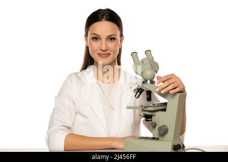 Portrait of female smiling scientist with microscope  on a white background Stock Photo