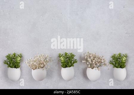 Easter composition. White eggs with funny faces painted on the table. A small bouquet in an egg. The minimal concept of Easter. An Easter card with a Stock Photo