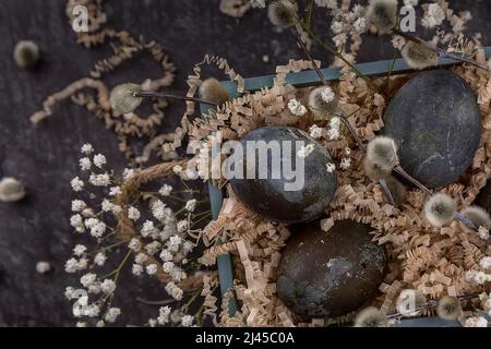 Easter composition with dark colored eggs in a wooden box. Willow branch. The minimal concept of Easter. An Easter card with a place for the text. Stock Photo