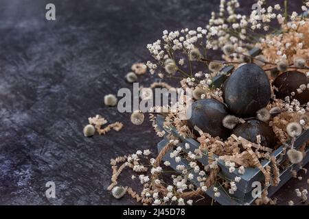 Easter composition with dark colored eggs in a wooden box. Willow branch. The minimal concept of Easter. An Easter card with a place for the text. Stock Photo
