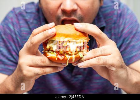 Eastern man looking at crispy chicken burger and is about to eat it. Stock Photo