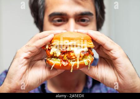 Eastern man looking at crispy chicken burger and is about to eat it. Stock Photo