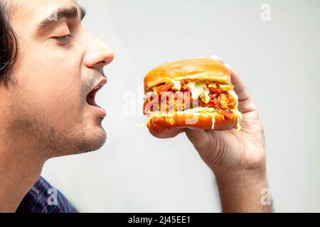 Eastern man looking at crispy chicken burger and is about to eat it. Stock Photo