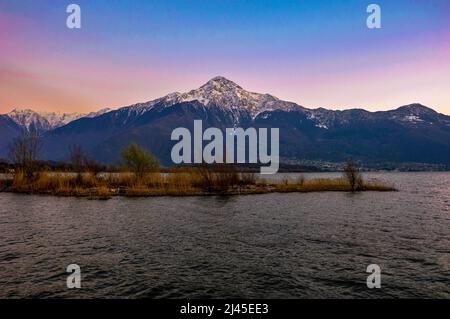 Snowy mountain peak at sunset towering over Lake Como, Italy Stock Photo