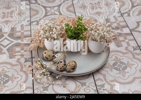 Easter composition. White eggs with funny faces painted on the table. A small bouquet in an egg. The minimal concept of Easter. An Easter card with a Stock Photo