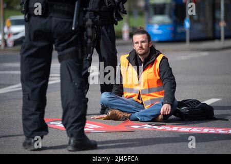 12 April 2022, Hessen, Frankfurt/Main: A demonstrator got stuck on a street during a protest by the group 'Last Generation'. The group is calling for an immediate halt to all investment in and new expansion of fossil fuel infrastructure. Photo: Sebastian Gollnow/dpa Stock Photo