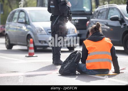 12 April 2022, Hessen, Frankfurt/Main: A demonstrator got stuck on a street during a protest by the group 'Last Generation'. The group is calling for an immediate halt to all investment in and new expansion of fossil fuel infrastructure. Photo: Sebastian Gollnow/dpa Stock Photo