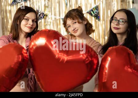 Valentine's Day. Beauty girls with red heart shaped air balloons having fun. birthday party Stock Photo