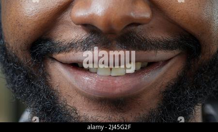 Macro shot of man moving his lips in front of camera and smiling, showing positive facial expression. Healthy person with natural skin showing candid smile, having short beard. Authentic emotions. Stock Photo