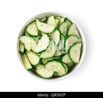 Cucumbers cut into pieces in a bowl, isolated on a white background. Top view Stock Photo