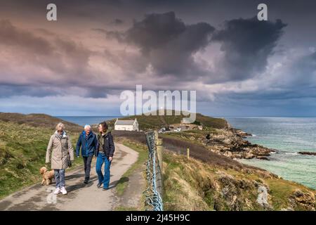 Walkers and their pet dog walking on the coast path from Towan Head on the coast of Newquay in Cornwall in the UK. Stock Photo