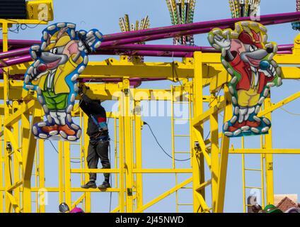 Munich, Germany. 12th Apr, 2022. A man assembles a ride being set up for the upcoming Spring Festival. Credit: Peter Kneffel/dpa/Alamy Live News Stock Photo