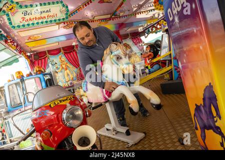 Munich, Germany. 12th Apr, 2022. A man cleans the various figures of a children's ride for the upcoming spring festival. Credit: Peter Kneffel/dpa/Alamy Live News Stock Photo