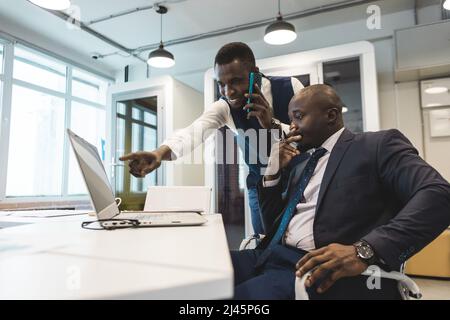 Two African American business partners are working on a laptop together on a joint project. Mutual assistance and establishment of social contacts Stock Photo