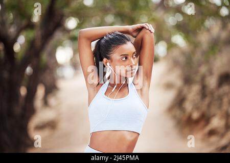 My arms get stronger everyday. Shot of a young woman stretching before a jog. Stock Photo