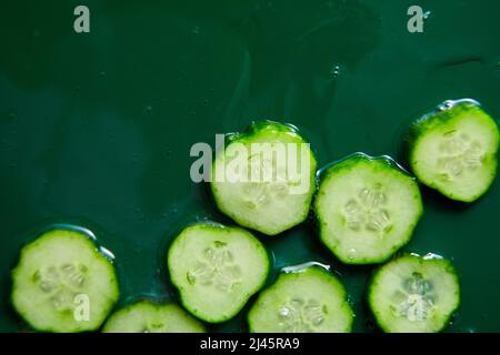 Flat lay cucumber slices with gel on green background, natural medicinal plant for organic cosmetics, alternative medicine, health and beauty spa conc Stock Photo