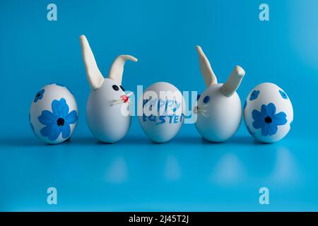 Easter composition with Easter eggs decorated flowers and Easter bunny. Blue background, copy space. Stock Photo