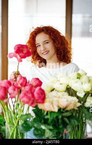 Florist makes a bouquet of peonies. Red-haired girl Stock Photo