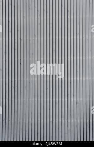 Architectural detail in close-up of grey corrugated steel industrial building facade with vertical lines forming symmetric abstract pattern Stock Photo