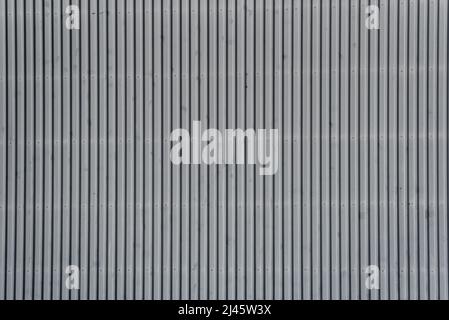 Architectural detail in close-up of grey corrugated steel industrial building facade with vertical lines forming symmetric abstract pattern Stock Photo