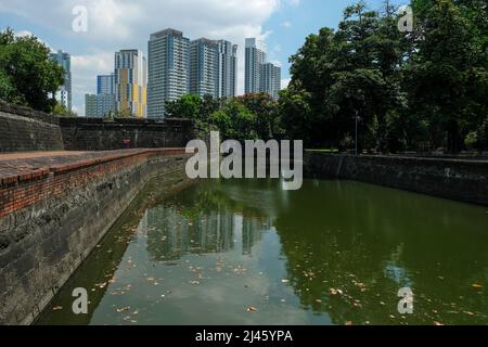 Views of the Fort Santiago moat with Manila's skyscrapers in the background. Intramuros in Manila, Philippines. Stock Photo