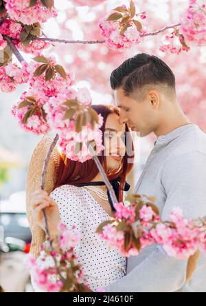 Couple in love cuddling outdoors. Romantic season.Tender love. Couple sakura tree background. Man and pretty woman enjoying pink cherry blossom. Roman Stock Photo