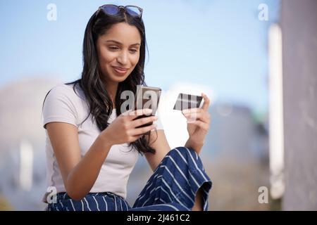 Student loans are relentless. Shot of a beautiful young student using her phone while sitting outside. Stock Photo