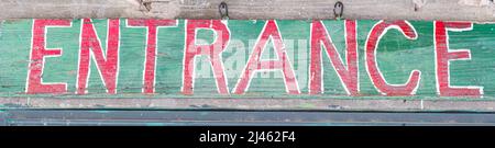 Weathered old wooden hand painted entrance sign Stock Photo