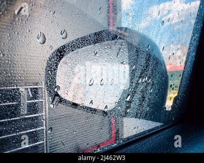 Wet wing mirror in car wash self-service, water drops on glass Stock Photo