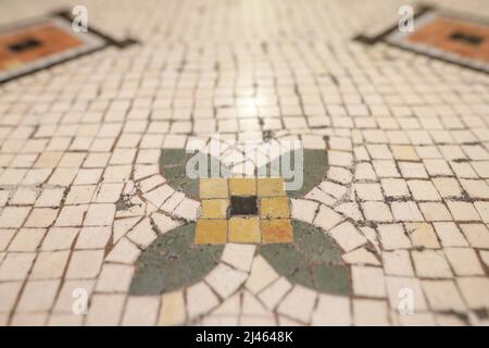 Shallow depth of field (selective focus) details with mosaic tiles on the floor of an old building in Bucharest. Stock Photo