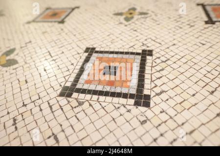 Shallow depth of field (selective focus) details with mosaic tiles on the floor of an old building in Bucharest. Stock Photo