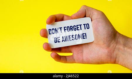 Don't forget to be cool business card in a male hand on a yellow background. Motivation for action Stock Photo