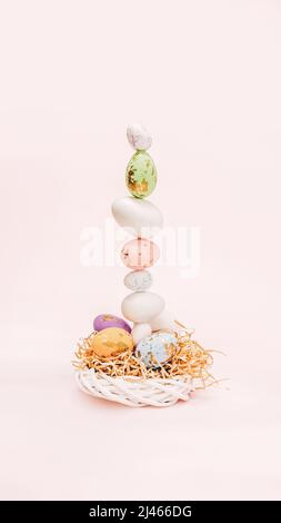 Easter concept made of pastel eggs, wicker wooden wreath and bright decorative hay. Easter eggs are different sizes and decorated with effects. The co Stock Photo